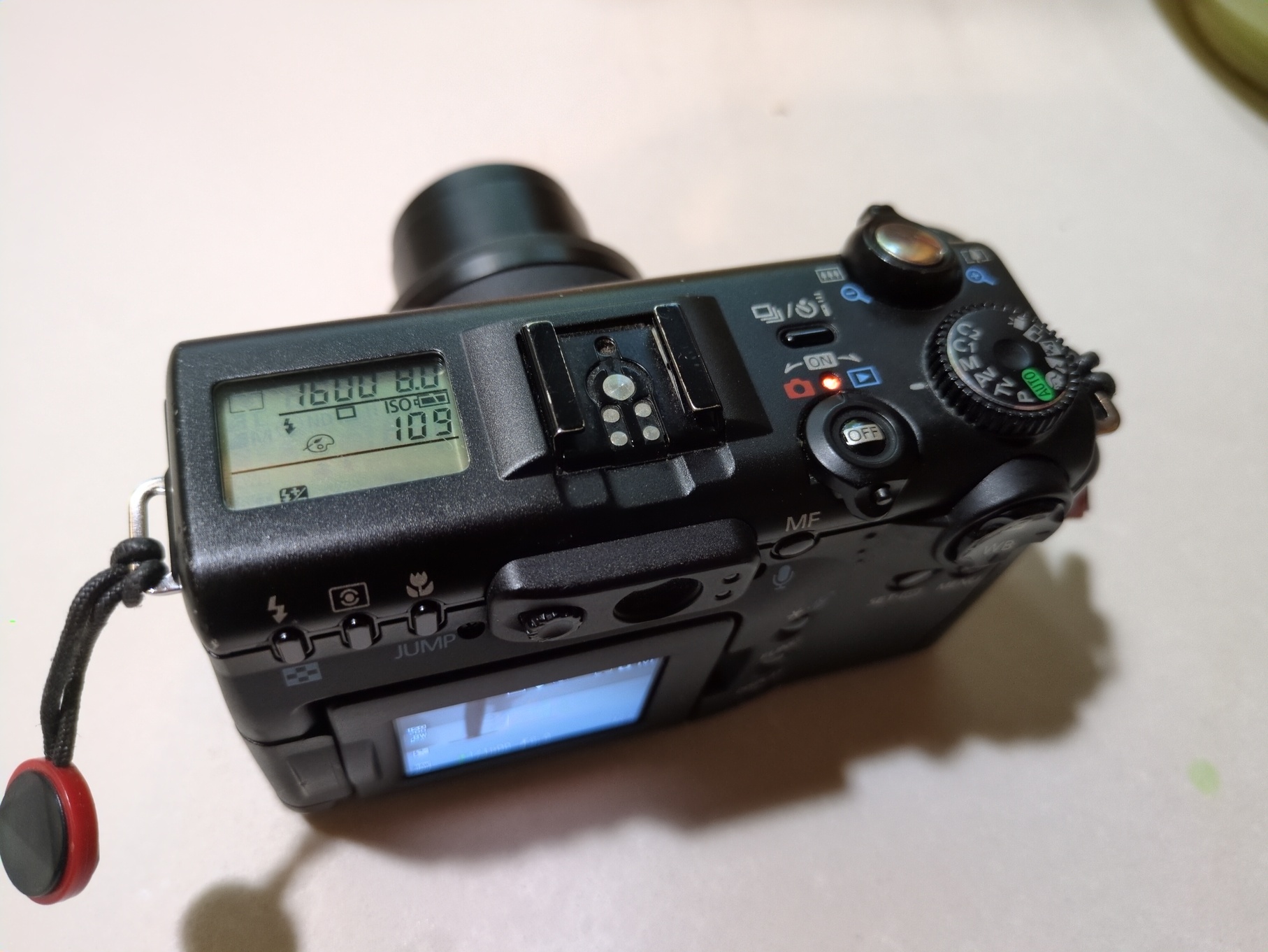 The Canon PowerShot G5 from the back, showing the top down system setting screen and various mode buttons.